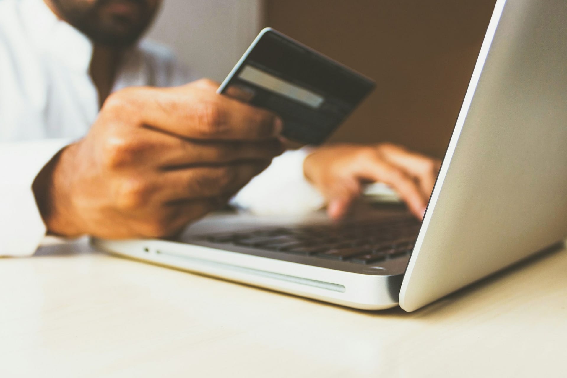 A payment card held beside an open laptop